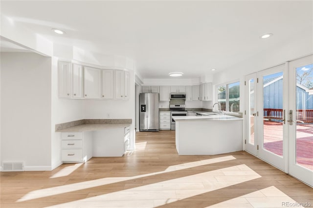 kitchen featuring french doors, light hardwood / wood-style flooring, kitchen peninsula, stainless steel appliances, and white cabinets