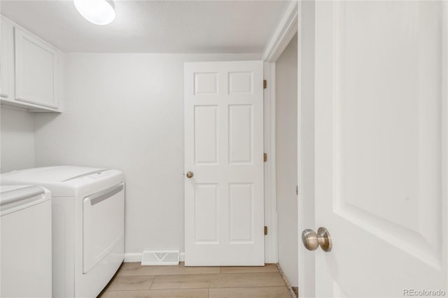 laundry room featuring washer and dryer, cabinets, and light wood-type flooring