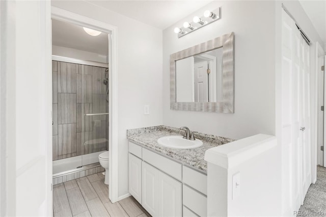 bathroom featuring vanity, an enclosed shower, and toilet