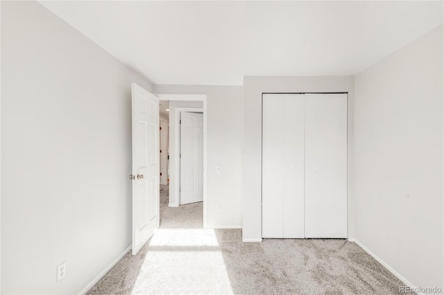 unfurnished bedroom featuring light colored carpet and a closet