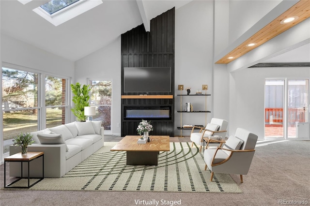 carpeted living room featuring high vaulted ceiling, a fireplace, and a skylight