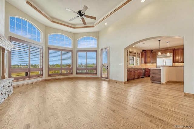 unfurnished living room with a raised ceiling, ceiling fan, light hardwood / wood-style flooring, and ornamental molding