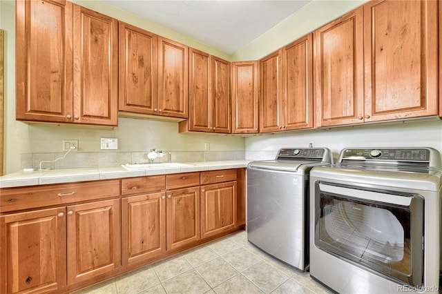 washroom featuring independent washer and dryer, cabinets, light tile patterned floors, and sink