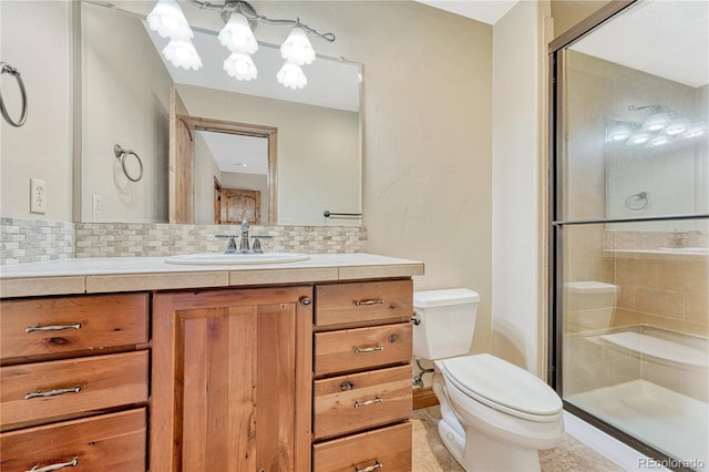 bathroom with backsplash, vanity, a shower with shower door, and toilet