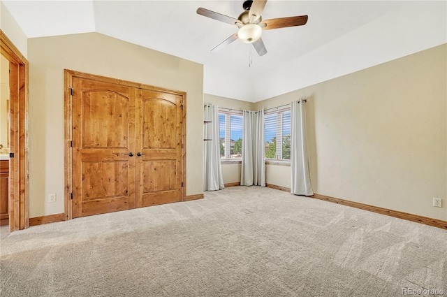 unfurnished bedroom with light carpet, a closet, ceiling fan, and lofted ceiling