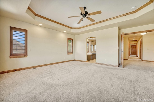 carpeted spare room featuring a tray ceiling, crown molding, ceiling fan, and a healthy amount of sunlight