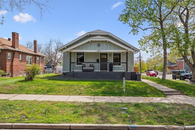 bungalow-style house featuring a front lawn, board and batten siding, and covered porch