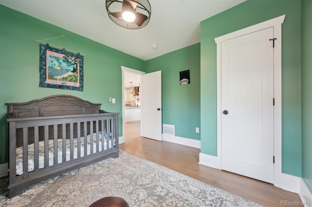 bedroom featuring baseboards, visible vents, and wood finished floors