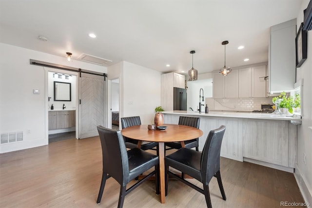 dining room featuring a barn door, recessed lighting, baseboards, wood finished floors, and visible vents