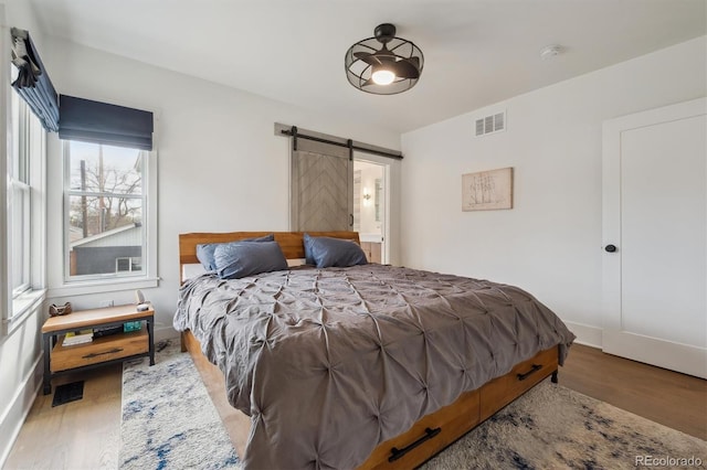 bedroom with visible vents, a barn door, and wood finished floors