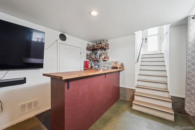 bar featuring visible vents, finished concrete flooring, stairway, a bar, and recessed lighting