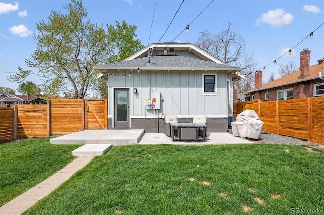 rear view of property with a fenced backyard, board and batten siding, a patio area, and a yard