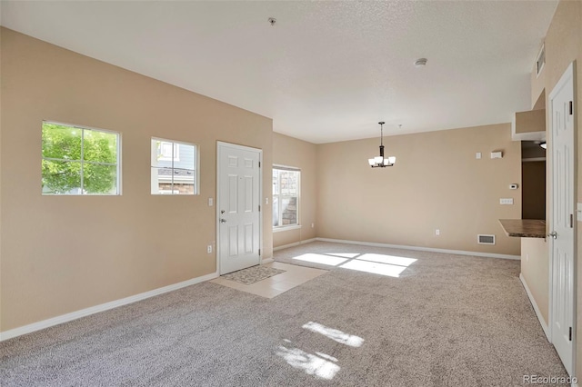 spare room with a chandelier, carpet floors, and baseboards