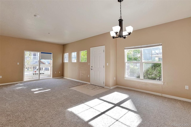 entryway featuring light colored carpet, a chandelier, and baseboards