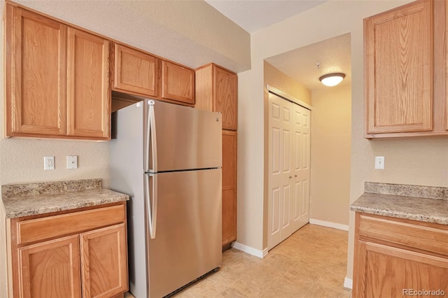 kitchen with freestanding refrigerator, light countertops, and baseboards
