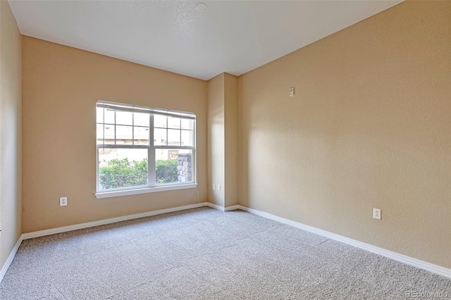 empty room featuring carpet and baseboards