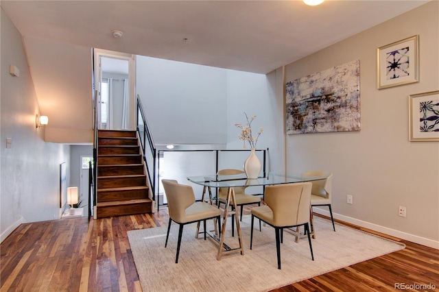 dining space with a wealth of natural light, stairs, baseboards, and wood finished floors