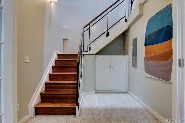 stairs featuring electric panel, baseboards, and carpet