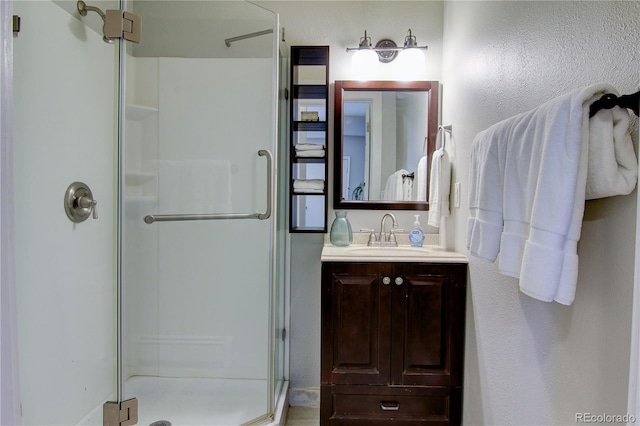 full bath with a shower stall, vanity, and a textured wall