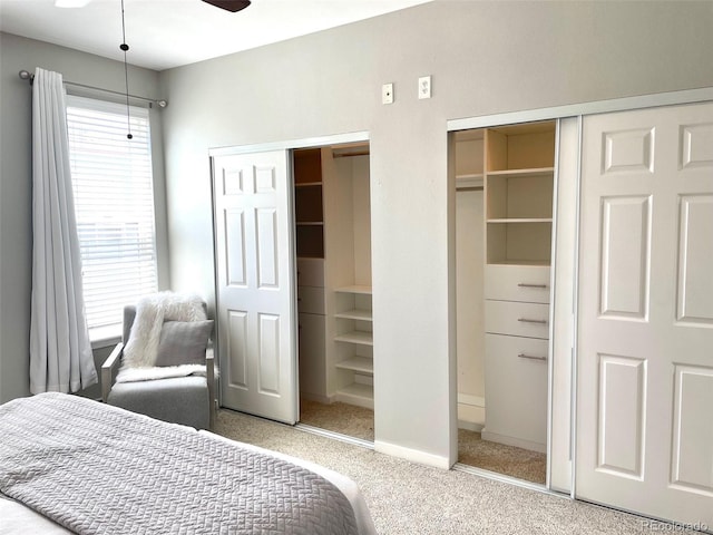 carpeted bedroom featuring baseboards and two closets