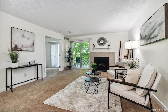 carpeted living room with a tiled fireplace and a textured ceiling