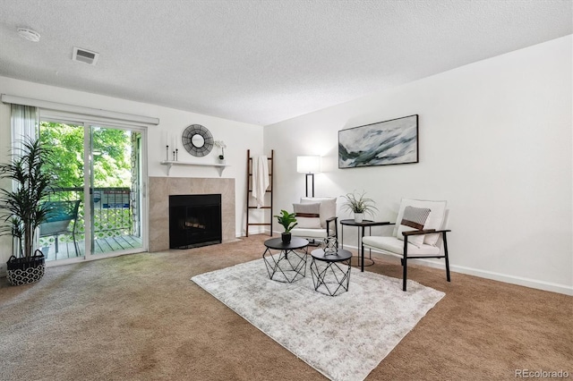 living room with a tile fireplace, a textured ceiling, and carpet