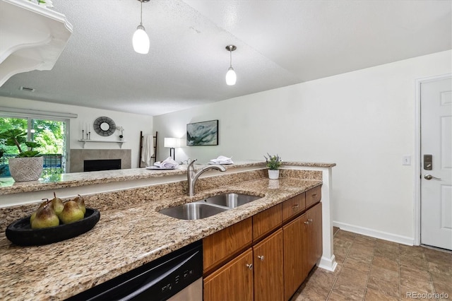 kitchen featuring sink, a tiled fireplace, a textured ceiling, and pendant lighting