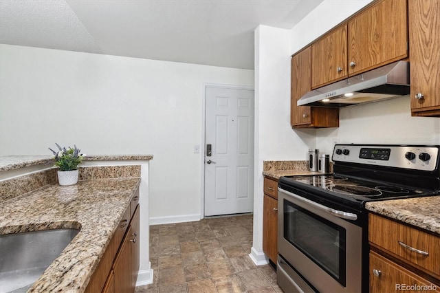 kitchen with light stone counters, electric stove, and a textured ceiling