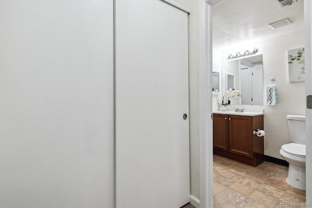 bathroom with toilet, a textured ceiling, and vanity