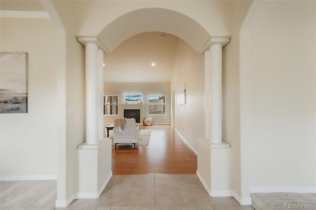 hallway featuring light tile patterned floors, baseboards, arched walkways, and ornate columns