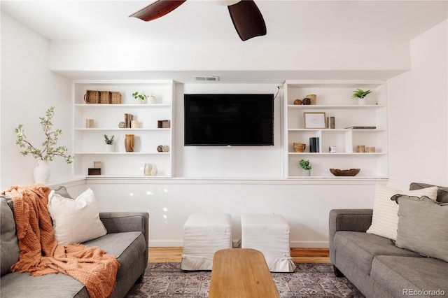 living room featuring dark hardwood / wood-style floors, built in features, and ceiling fan