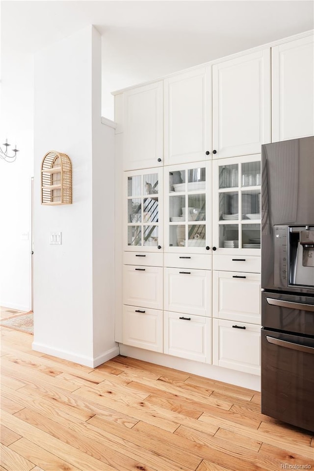 kitchen featuring white cabinetry, light hardwood / wood-style flooring, and black fridge