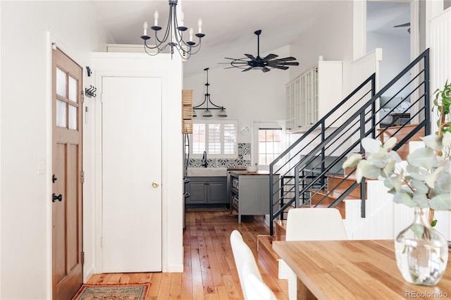 foyer featuring ceiling fan with notable chandelier, sink, hardwood / wood-style floors, and high vaulted ceiling