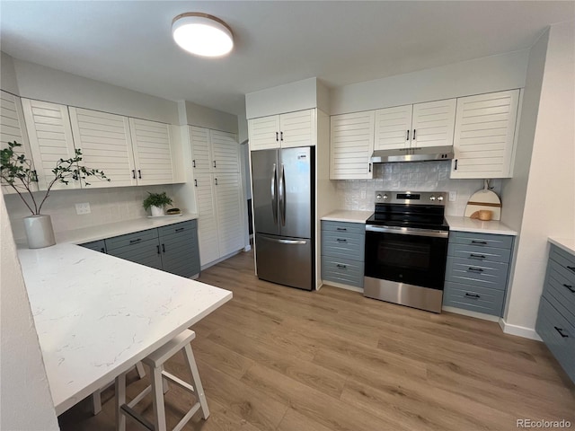 9540 King Way, Westminster, CO 80031 - kitchen featuring appliances with stainless steel finishes, under cabinet range hood, light wood-style floors, backsplash, and light countertops