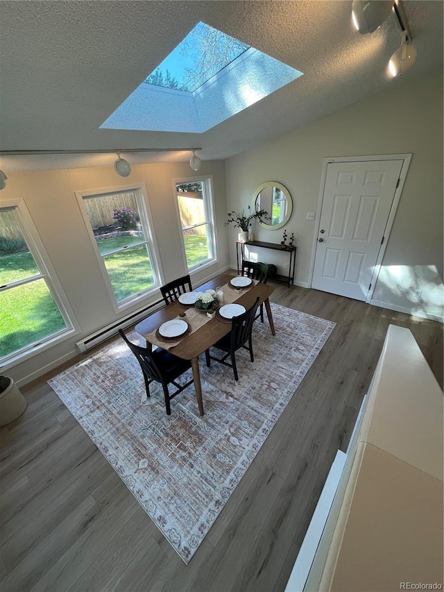 9540 King Way, Westminster, CO 80031 - dining area with a skylight, a textured ceiling, rail lighting, wood finished floors, and a baseboard radiator