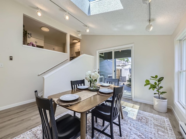 9540 King Way, Westminster, CO 80031 - dining space with track lighting, a skylight, a textured ceiling, a baseboard heating unit, and light wood-type flooring