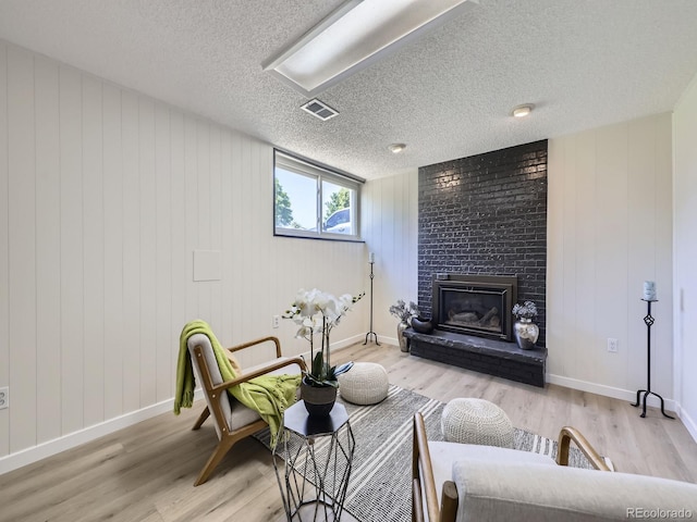 9540 King Way, Westminster, CO 80031 - living area featuring light wood-type flooring, a textured ceiling, and a brick fireplace