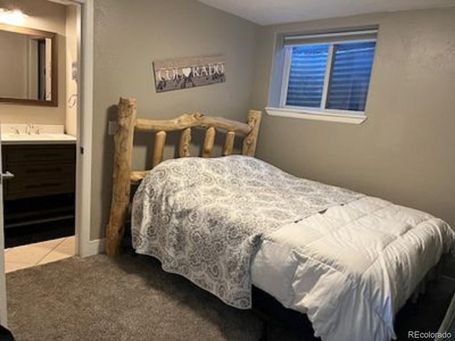 carpeted bedroom featuring tile patterned flooring, vaulted ceiling, ensuite bath, and a sink