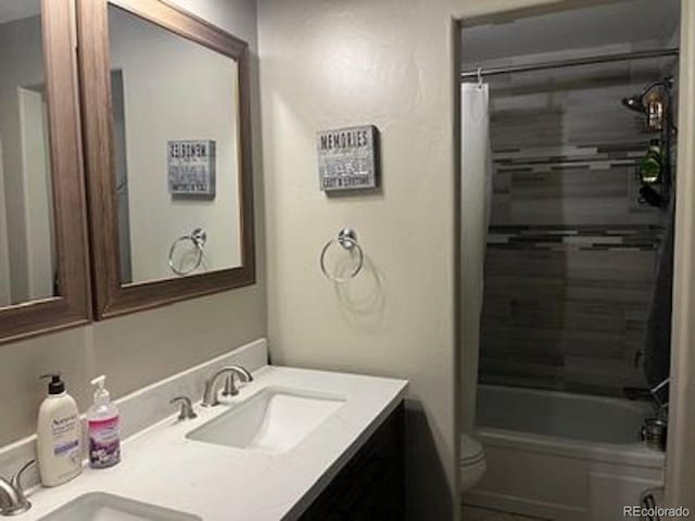 bathroom featuring a sink, shower / bath combo with shower curtain, toilet, and double vanity