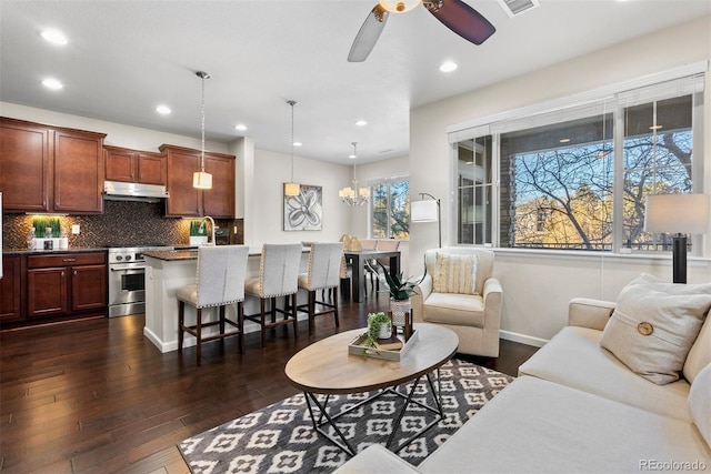 living room featuring dark wood-type flooring and ceiling fan with notable chandelier