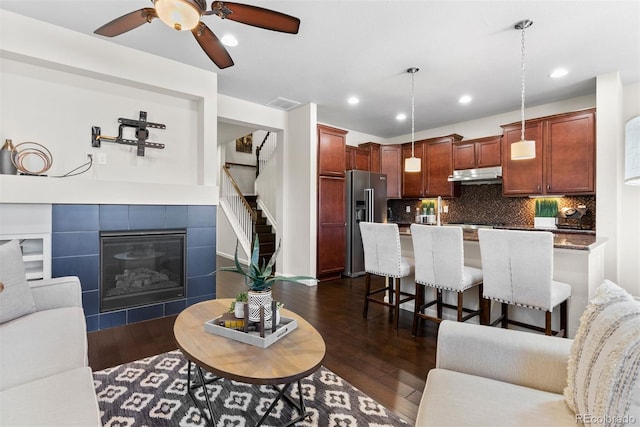 living room with a tile fireplace, ceiling fan, and dark hardwood / wood-style flooring