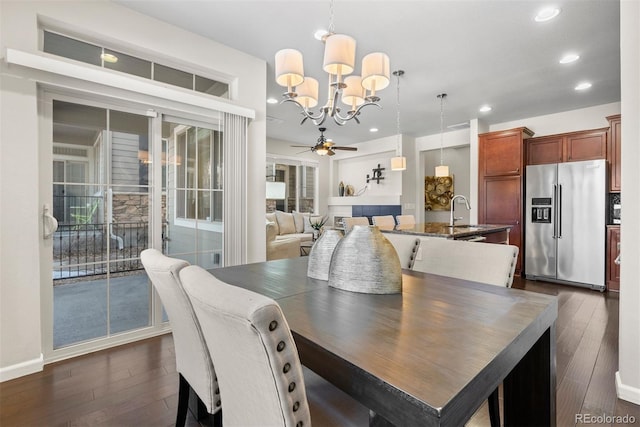 dining space with dark hardwood / wood-style flooring, sink, and ceiling fan with notable chandelier