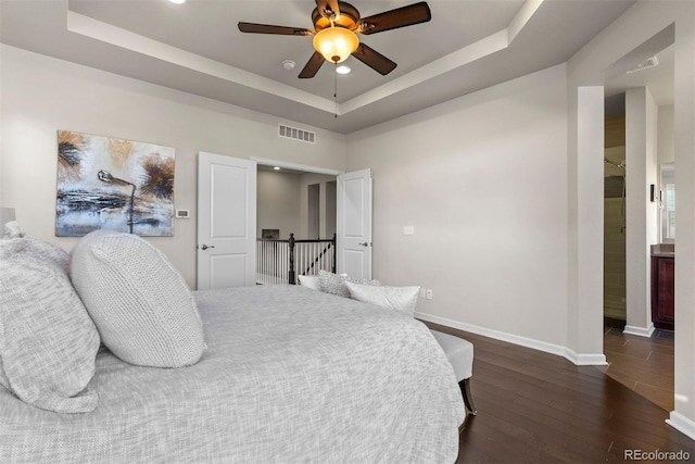 bedroom with dark hardwood / wood-style floors, ceiling fan, and a tray ceiling