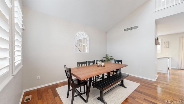 dining room featuring hardwood / wood-style flooring, high vaulted ceiling, and a wealth of natural light