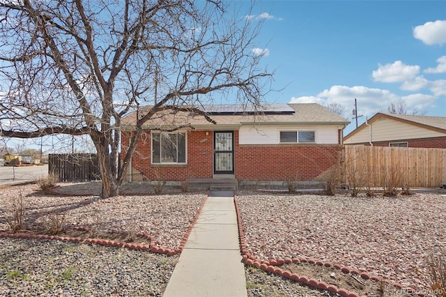 7180 Zuni St, Denver, CO 80221 - view of front of property with brick siding, roof mounted solar panels, roof with shingles, and fence