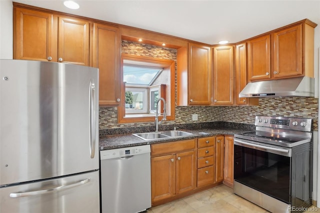 7180 Zuni St, Denver, CO 80221 - kitchen with under cabinet range hood, decorative backsplash, brown cabinets, appliances with stainless steel finishes, and a sink