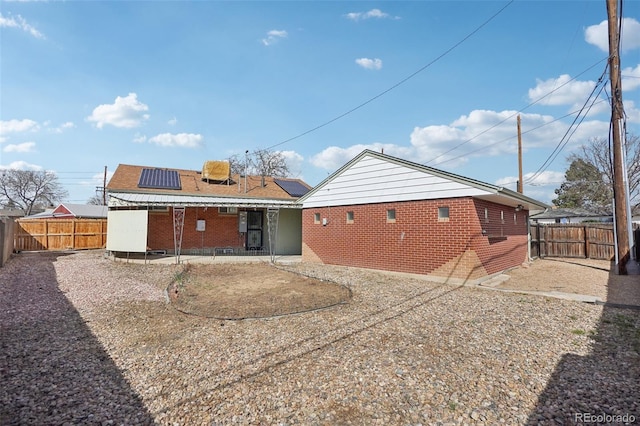 7180 Zuni St, Denver, CO 80221 - rear view of house with a patio, a fenced backyard, brick siding, and roof mounted solar panels