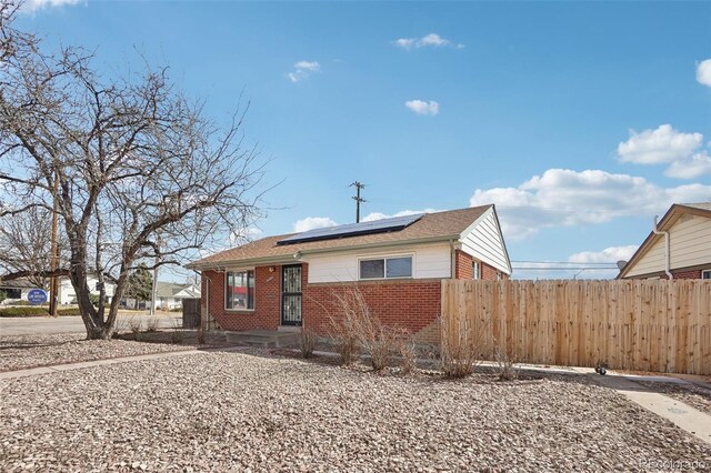 7180 Zuni St, Denver, CO 80221 - view of front of home featuring solar panels, fence, and brick siding