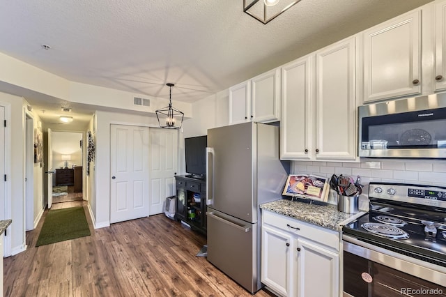 5757 S Algonquian Way Unit E, Aurora, CO 80016 - kitchen with appliances with stainless steel finishes, white cabinets, tasteful backsplash, dark wood finished floors, and light stone counters