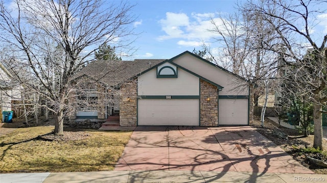 traditional-style house with a garage, stone siding, and driveway